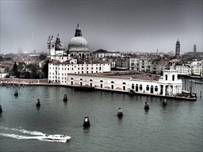 A view of Venice with a church and boats in the water on a cloudy day, church towers and historic