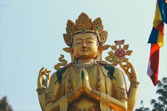 Ornate golden Avalokitesvara female Buddha statue against a clear blue sky background in Swayambhu