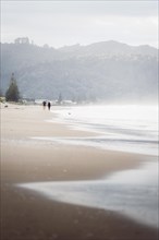 Walk on the beach at sunset, restless sea lapping waves on the beach, rocky landscape in the