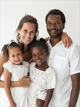 A cheerful multicultural family with two smiling children posing for a portrait, AI generated