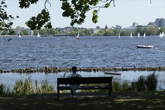Symbolic picture weather, leisure activity, summery spring, silhouette of a man on a park bench,