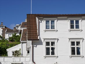 White wooden houses with red tiled roofs against a clear blue sky, white wooden houses with green