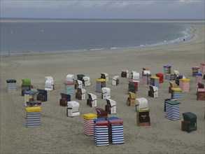 A multitude of colourful beach chairs on the extensive beach with the sea in the background, beach