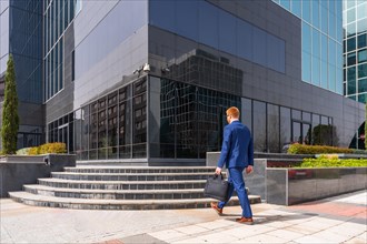 Horizontal rear view of a businessman arriving at the block office at work