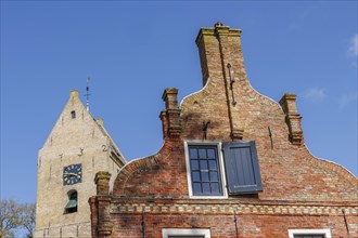 A bell tower and a brick house with a tiled roof and windows under a blue sky, historic houses and