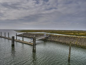 A view of the coast and the sea with a long jetty and cloudy sky, small jetty with a single-seater