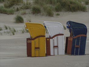 Close-up of three colourful beach chairs on an empty beach, colourful beach chairs on the beach and