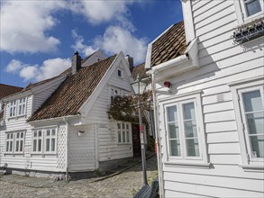 Cobbled street with white wooden houses and lanterns under a blue sky, white wooden houses with
