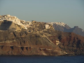 A coastline of Santorini with prominent cliffs and densely built houses dominating the rocky