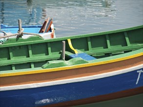 Close-up of a colourful boat in the water with dominating green and blue colours, many colourful
