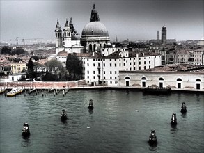 A view of Venice with a prominent church and surrounding buildings on a cloudy day, church towers