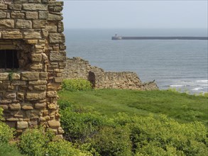 View of a historic ruin and the sea with a lighthouse in the background, ruins and old stone walls