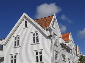 White wooden house with red tiled roof and several windows under blue sky, white wooden houses with
