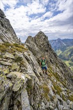 Mountaineer on a narrow mountain path, rocky pointed summit of the Raudenspitze or Monte Fleons,