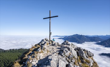 Summit cross at Ettaler Manndl, view over mountain landscape and sea of clouds, high fog in the