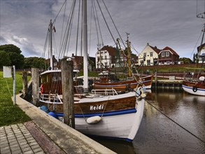 Several traditional boats are moored in the harbour, surrounded by historic houses. A stormy sky