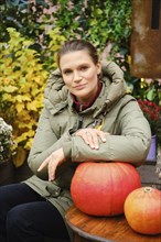 Outdoor portrait of a woman leaning on a pumpkin