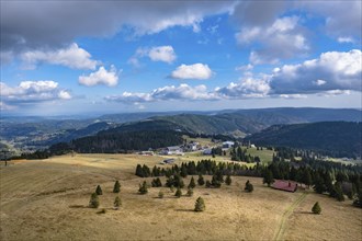 Wide hilly landscape with scattered buildings and a clear sky with clouds, Feldberg, Germany,