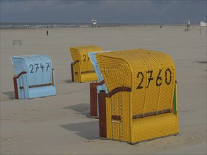 Yellow and blue beach chairs in a sandy landscape on a cloudy day, colourful beach chairs on the