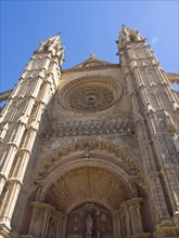 Detailed Gothic facade with impressive archway, arch structure and statues under a clear blue sky,