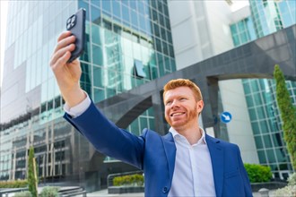 Confident and happy businessman smiling while taking selfie standing in the city