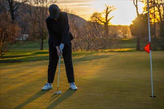 Female Golfer Concentration on the Putting Green on Golf Course in Sunset in Switzerland