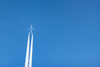 An aeroplane leaves contrails in the clear blue sky, Germany, Europe
