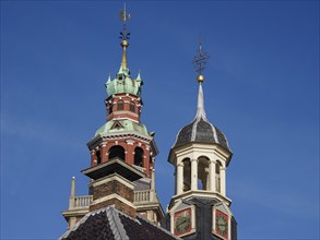 Two historic church towers with weather vane and clock under a blue sky, two towers of historic