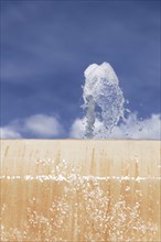 Stream of water coming out of a public fountain with a blue sky in the background
