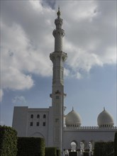Slender minaret and domes of a mosque against a cloudy sky, the grandiose architecture impresses,