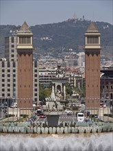 Central fountain and historic towers in an urban setting, with mountains in the background, two red