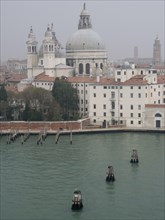 Historic Venetian buildings with domes and water, in a misty atmosphere, church towers and historic