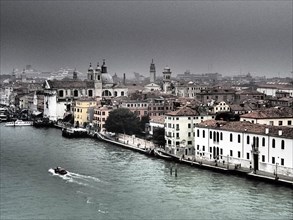 Foggy view of Venice's buildings along a canal, church towers and historic buildings along a large