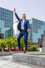 Vertical photo of a successful businessman jumping celebrating raising the arm in the city