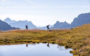 Mountaineers reflected in the lake in front of mountain landscape, mountain lake and silhouettes of
