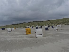 Many beach chairs, yellow and white, are spread over the beach under a cloudy sky, colourful beach