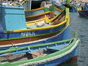 Colourful fishing boats in the harbour moored to the shore with ropes and floating in the water,