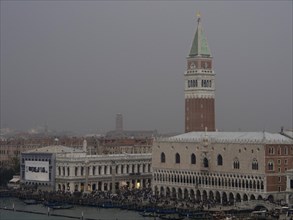 Campanile of Venice, surrounded by historic buildings, under a misty sky, church towers and