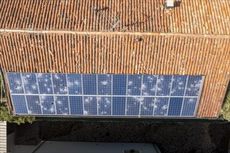 Aerial image of a terracotta tiled roof with a row of damaged solar panels