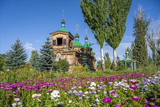 Colourful flowers in front of the Russian Orthodox Church Cathedral of the Holy Trinity, wooden