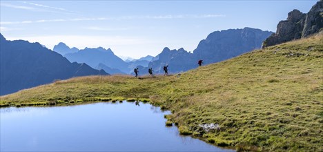 Group of mountaineers in front of mountain landscape, mountain lake and silhouettes of rocky