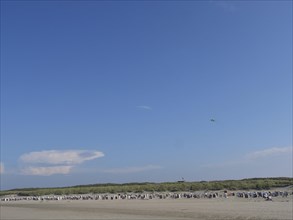 Spacious beach in front of dunes with clear blue sky and few clouds on the horizon, dunes and beach