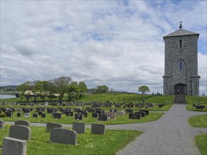 Stone church in a cemetery with numerous gravestones in a quiet, rural setting, old stone church