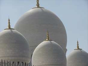 The immaculately detailed domes of the mosque stand out against the sunny sky, large mosque with