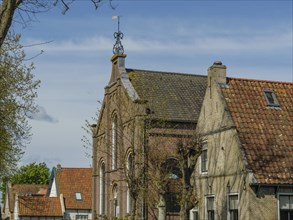 Row of old houses with red tiled roofs, surrounded by trees and a clear blue sky, historic houses