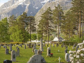 Cemetery in front of majestic mountains with gravestones, trees and flowers creating a calm and