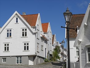 White wooden houses, streetlights and cobblestone street under blue sky, historic architecture with