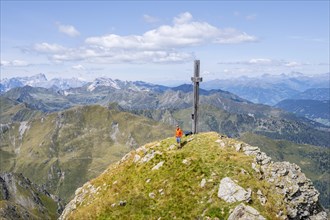 Mountaineer at the summit of the Hochspitz or Monte Vancomun with summit cross, mountain panorama,