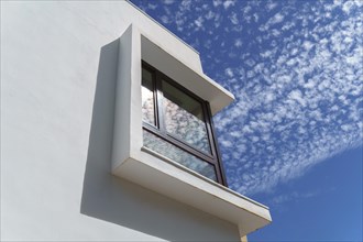 Low angle view of window in the corner of a modern building with blue sky with clouds