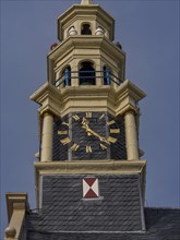 Close-up of a clock on a historic clock tower with blue and yellow decoration, tower with a golden